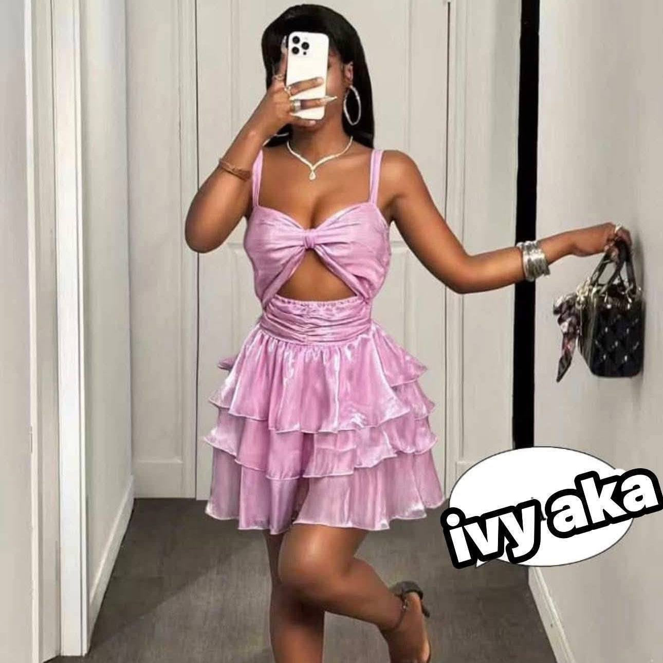 Person wearing a pink dress taking a mirror selfie in a hallway.