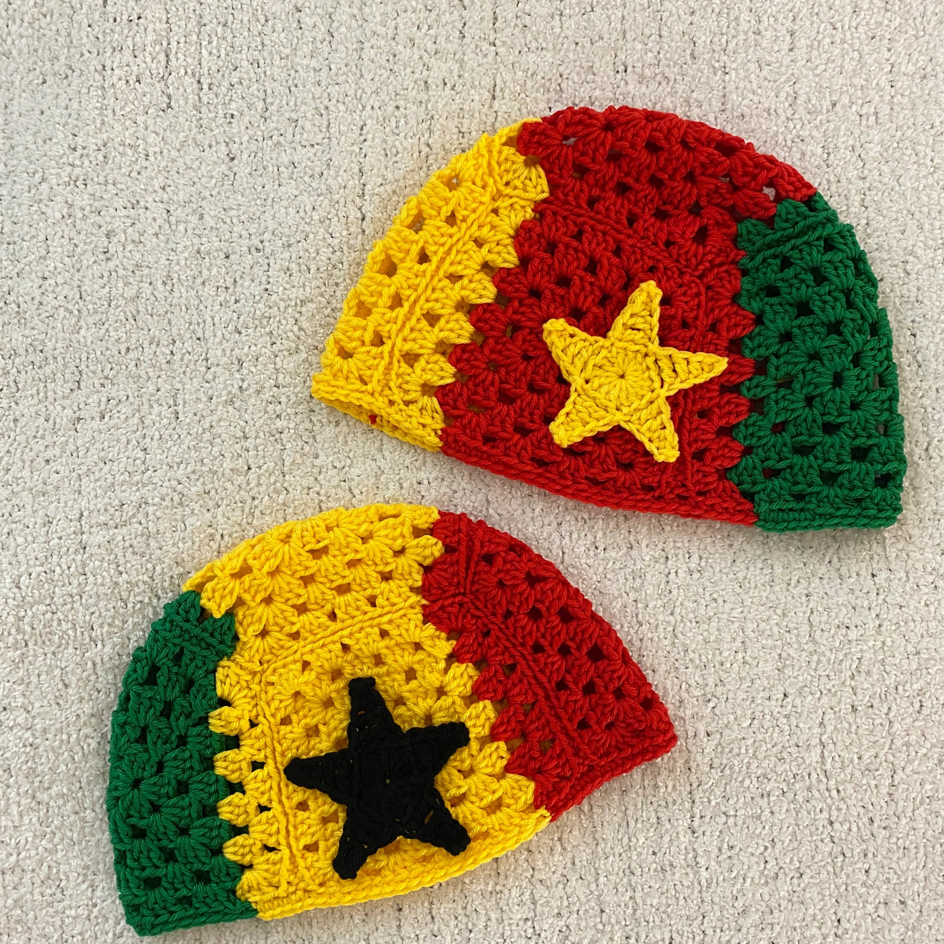 Two crocheted hats with Ghanaian flag colors and a star on a light gray background
