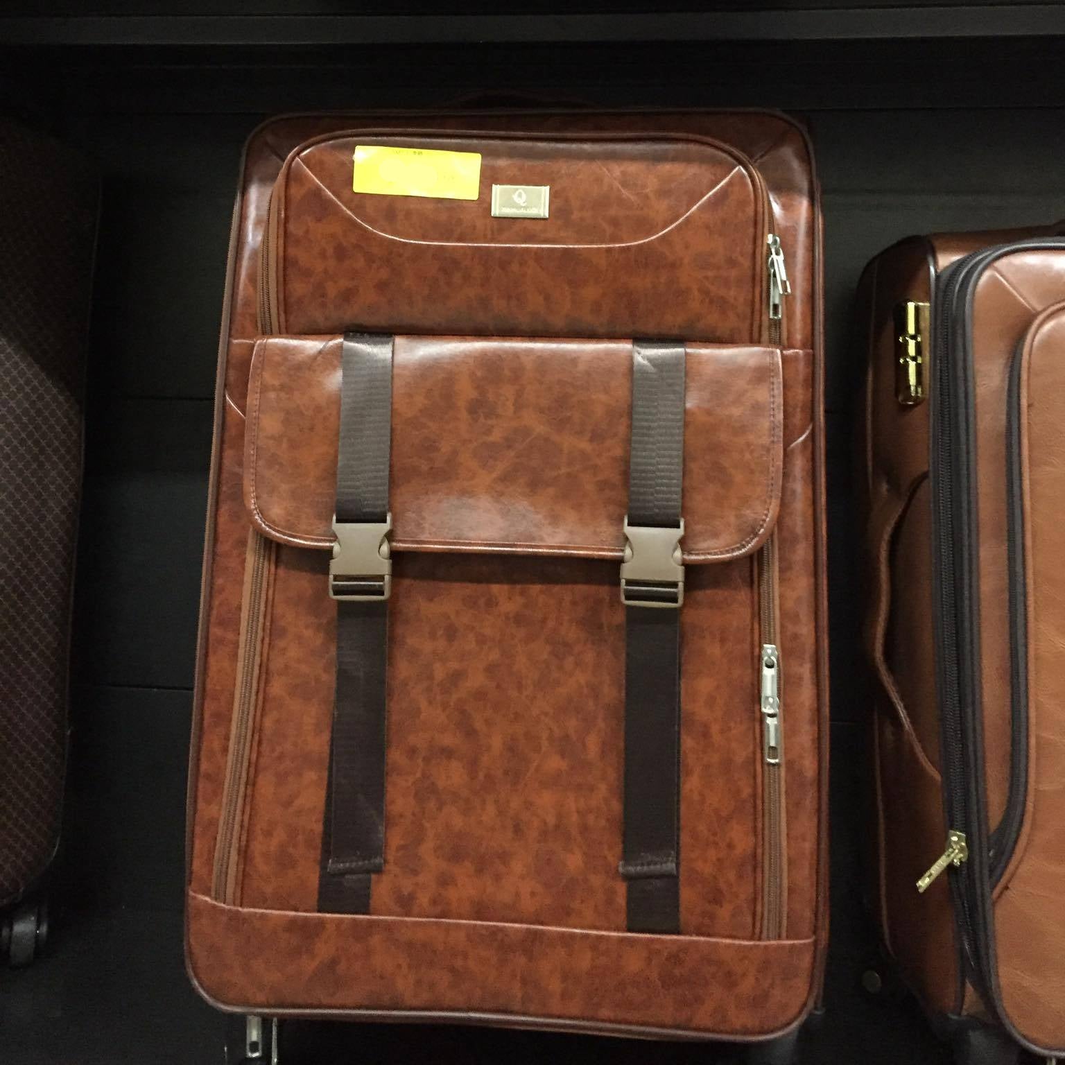 Brown leather suitcase with straps on a luggage rack