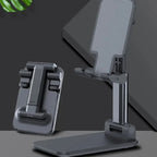 Two adjustable phone stands on a dark surface with a leaf in the corner.