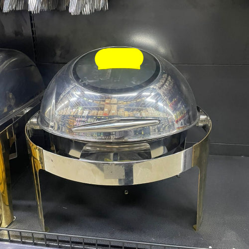 Metallic chafing dish with a clear dome lid on a gray shelf.