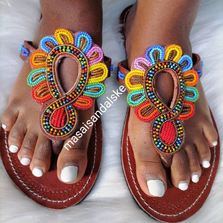 Colorful beaded sandals on feet with a white background