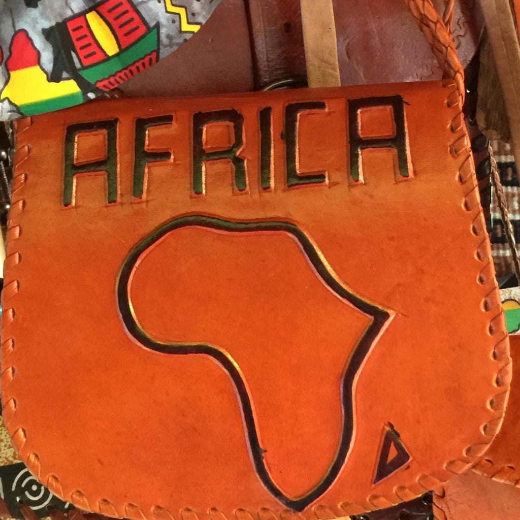 Brown leather bag with 'AFRICA' and a map design, surrounded by colorful fabric.
