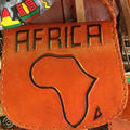 Brown leather bag with 'AFRICA' and a map design, surrounded by colorful fabric.