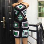 Mannequin wearing a black, green, and white crochet dress with geometric patterns against a door and wall background.