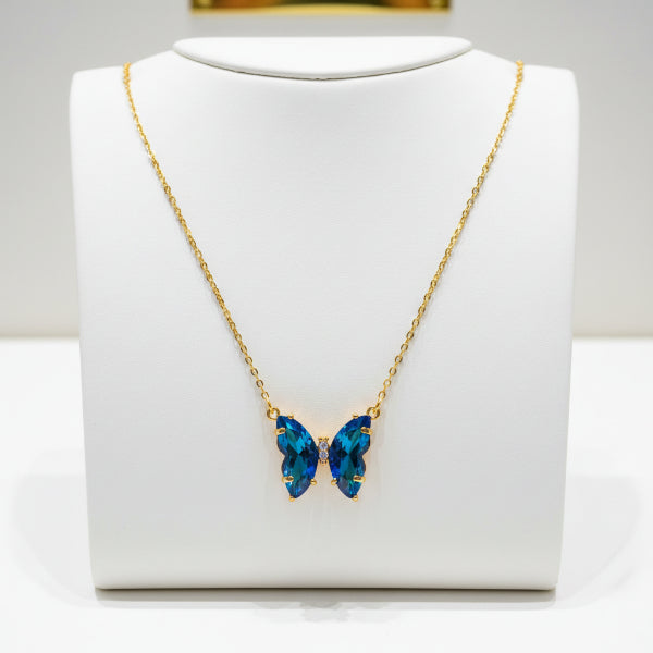 Necklace with a blue butterfly pendant on a white card, against a dark background