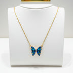 Necklace with a blue butterfly pendant on a white card, against a dark background