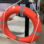 Red life buoy with a yellow patch on a rope in an indoor setting
