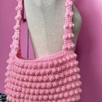 Pink crochet bag on a mannequin against a pink background