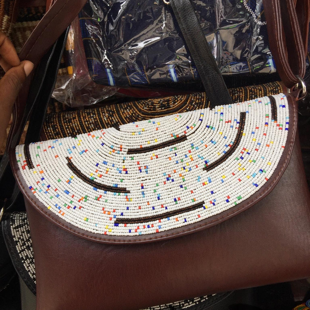 Beaded handbag with a colorful pattern held by a person.
