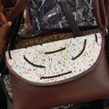 Beaded handbag with a colorful pattern held by a person.