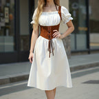 Woman wearing a white dress with a brown corset-style bodice on a city street.