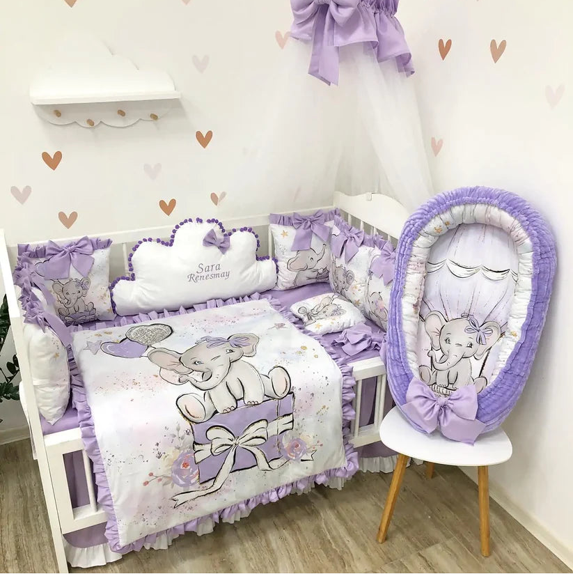 Baby crib set with purple and gray elephant design in a nursery.