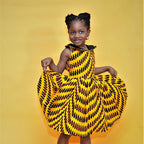 Young girl wearing a yellow and black patterned dress on a yellow background