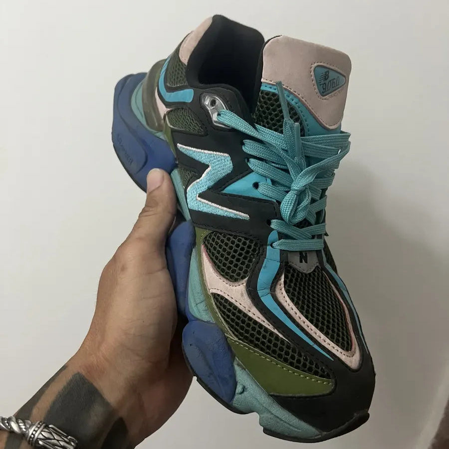 Colorful sneaker held by a hand against a plain background