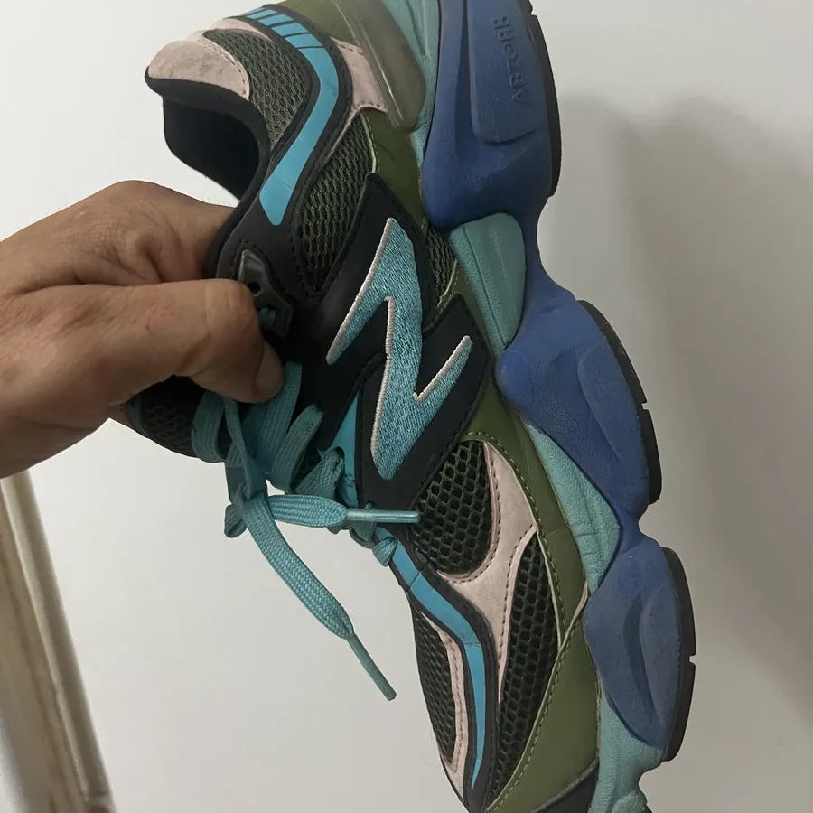 Multicolored sneaker held by a hand against a white background