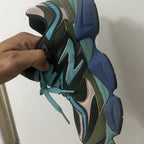 Multicolored sneaker held by a hand against a white background