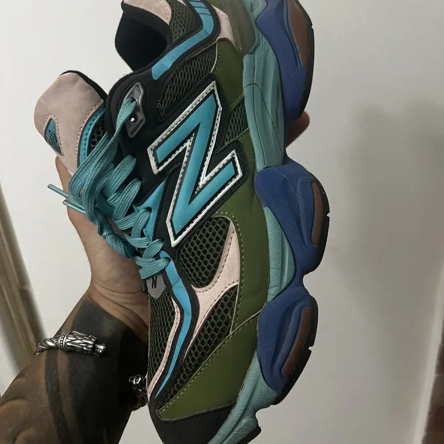 Multicolored sneaker with a prominent 'N' logo held by a person against a neutral background