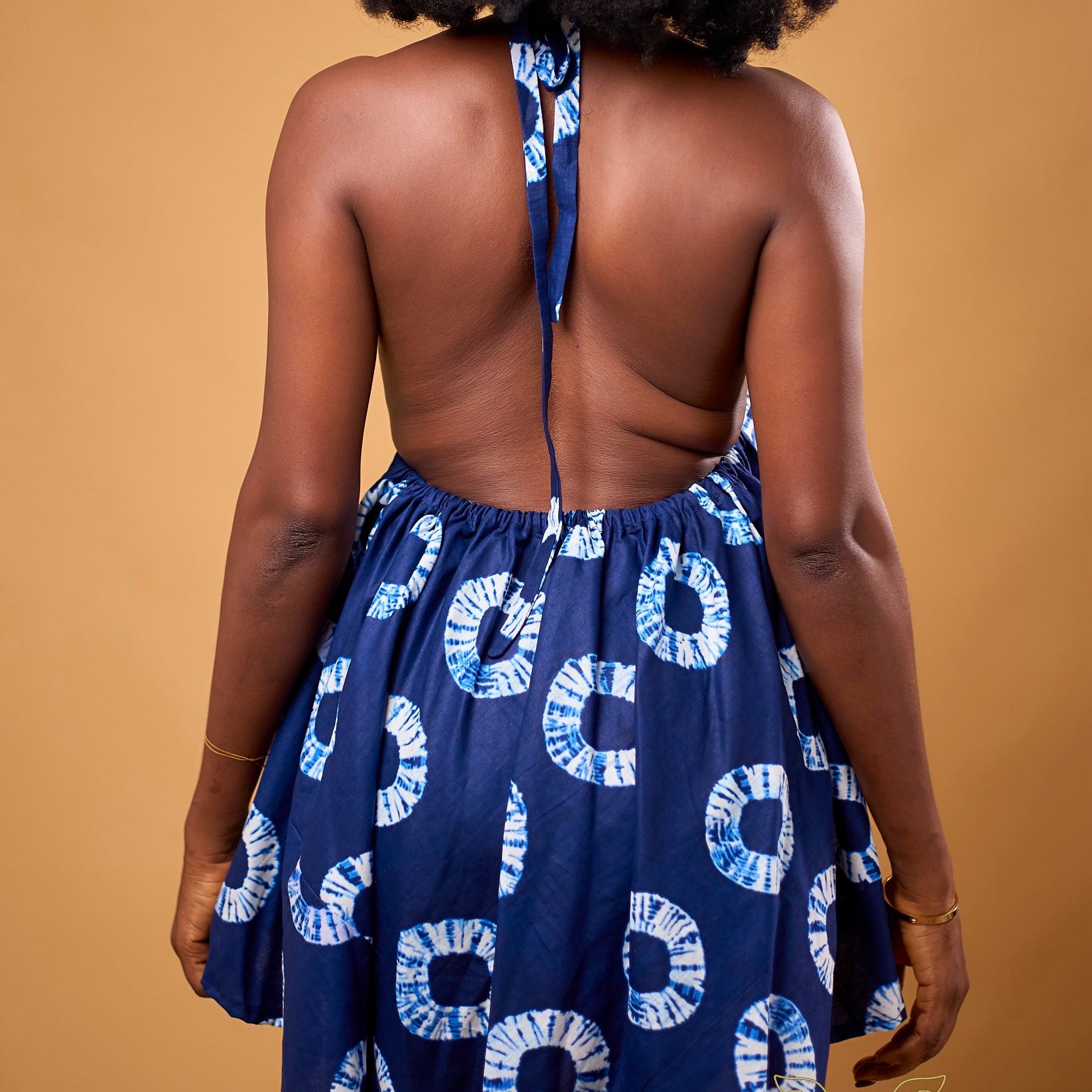 Person wearing a navy blue dress with white patterns on a beige background