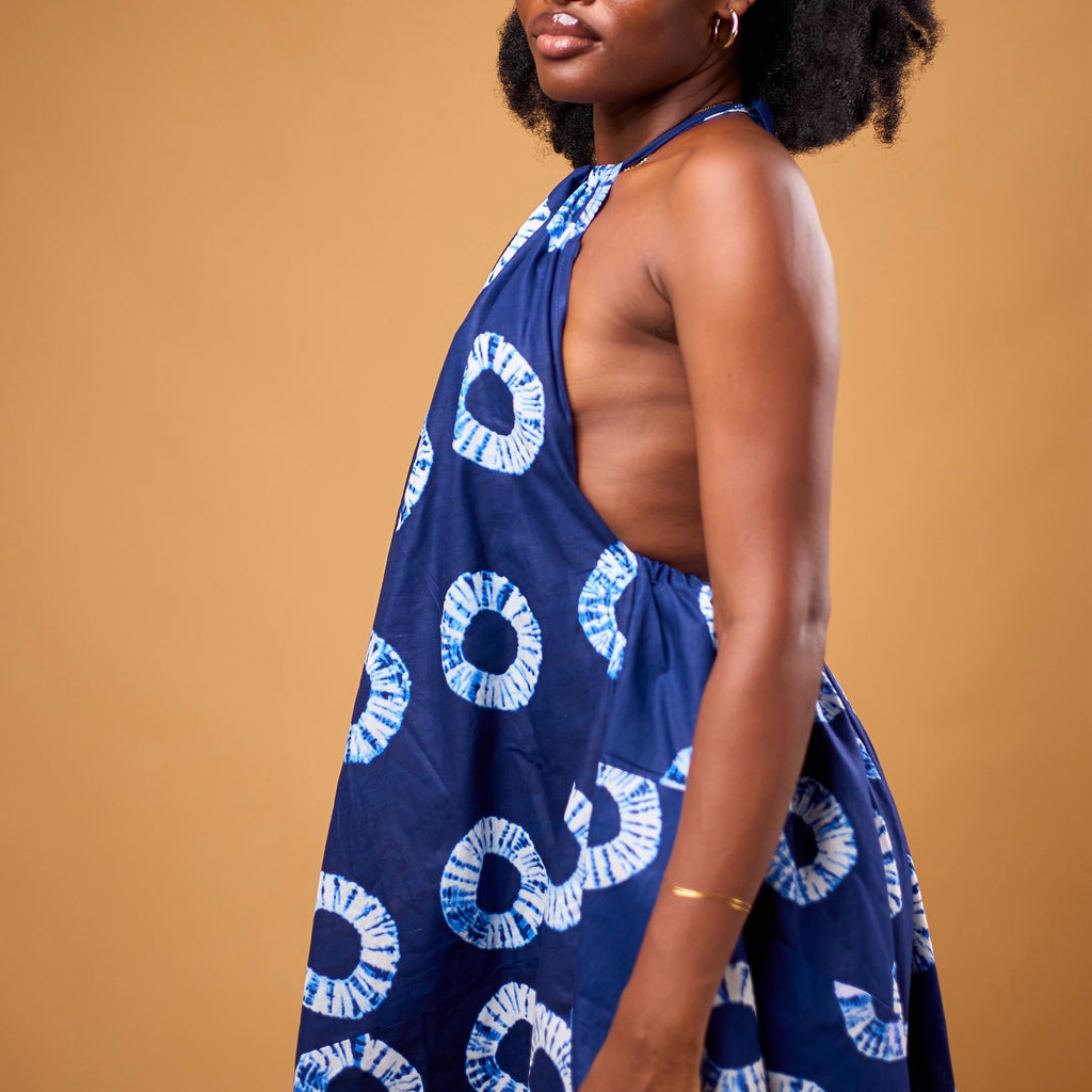 Woman wearing a blue dress with white patterns against a brown background