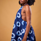 Woman wearing a blue dress with white patterns against a brown background