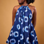 Woman wearing a blue and white patterned halter dress against a brown background