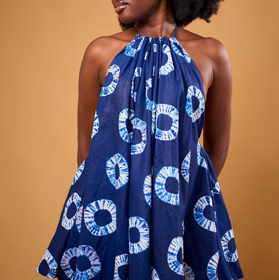 Woman wearing a blue and white patterned halter dress against a brown background