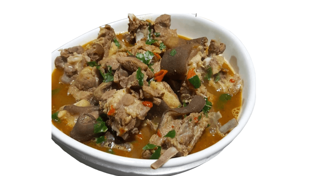Stir-fried chicken dish with vegetables in a white bowl on a white background. Goat Meat Pepper Soup from Town Bakery