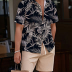 Man wearing a navy and white leaf-patterned shirt with beige shorts, holding a brown paper bag.
