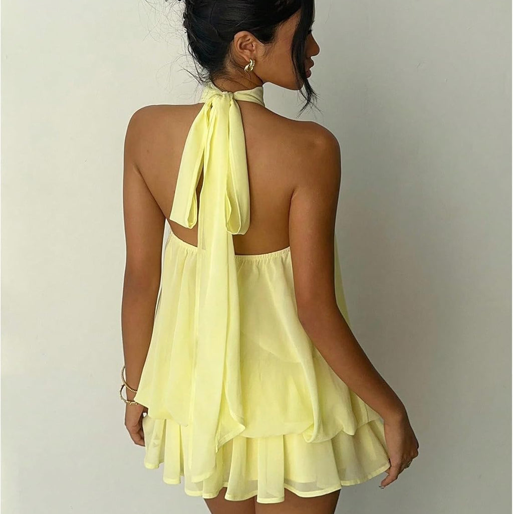 Woman wearing a yellow dress with a halter neck design on a plain background