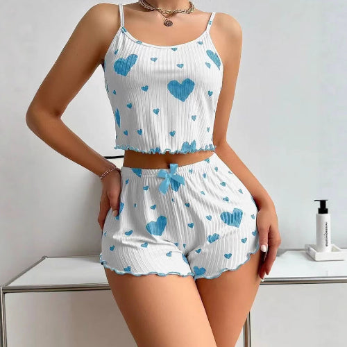 Woman wearing a white top and shorts set with blue heart patterns on a light background