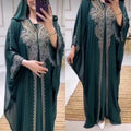 Green abaya with intricate silver embroidery worn by a person, displayed against a neutral background.