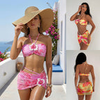 A three-panel collage showing a woman modeling a tropical floral bikini set in a bright outdoor setting. The main panel shows her from the front wearing a pink and yellow bikini with a large straw hat; the top-right panel shows the front of the matching bikini bottoms and halter top; the bottom-right panel shows the back of the bikini bottom and the back of the halter top.