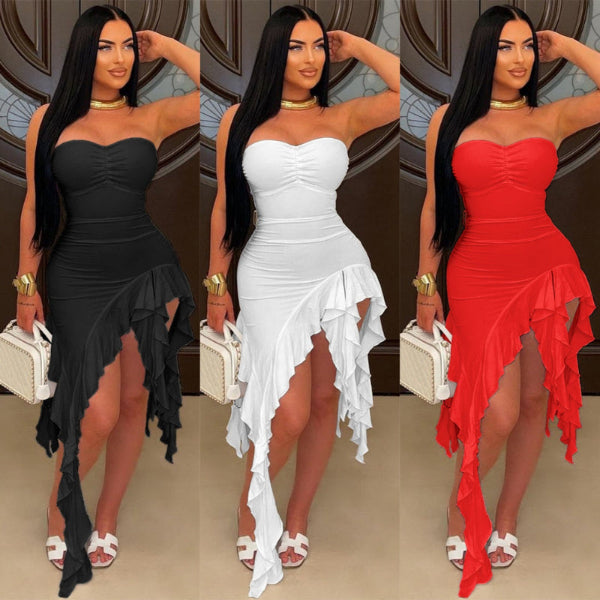 Three women modeling the same strapless ruffled asymmetrical dress in three color options: black, white, and red. Each model is shown full length against an ornate brown interior background, holding a small white handbag.