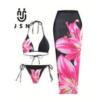 Three-piece women's bikini set on a white background, featuring a black halter top and matching side-tie bottoms with a large pink lily floral print, alongside a matching black midi skirt with the same floral pattern. The brand logo 'JSN' is visible in the top left.