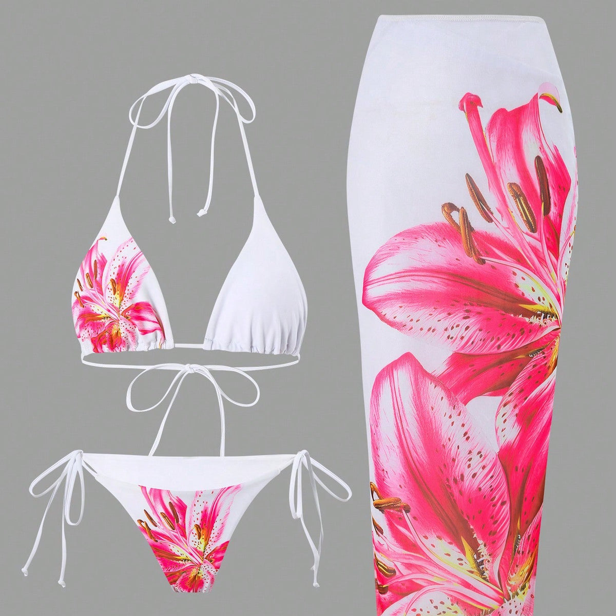 A white swimwear set featuring a halter bikini top and matching string bikini bottom, both printed with large pink and red lily flowers, shown alongside a matching white tube-style swim skirt with the same floral print, on a solid gray background.