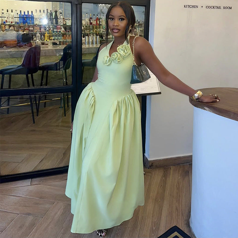 A woman wearing a sleeveless light mint green maxi dress with 3D floral embellishments on the bodice, standing in a restaurant or bar environment.