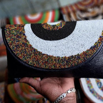 Hand holding a beaded clutch bag with colorful patterns in the background