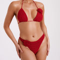 Woman wearing a red bikini with floral details on a white background