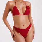 Woman wearing a red bikini with floral details on a white background