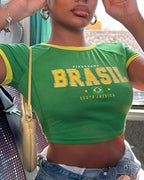 Person wearing a green 'Brasil' t-shirt with yellow accents, sitting inside a vehicle.