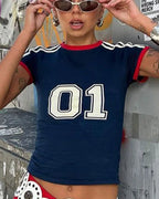 Person wearing a navy blue t-shirt with '01' on it, standing against a graffiti-covered wall.