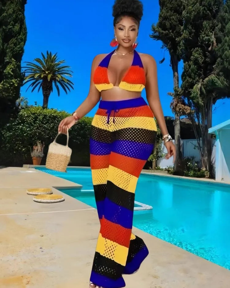 Woman in a colorful striped outfit standing by a pool with palm trees in the background