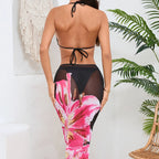 Woman wearing a black bikini with pink floral cover-up in a room with a plant and chair.