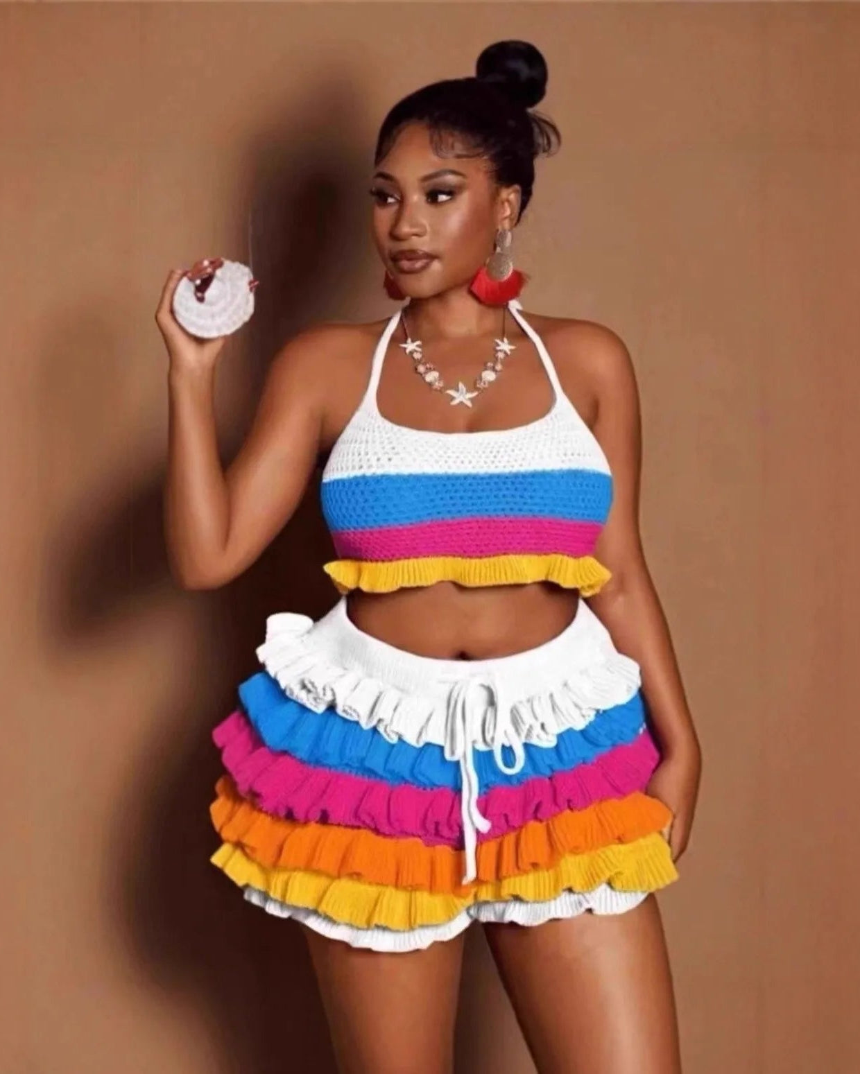 Woman wearing a colorful striped outfit with ruffled shorts against a brown background