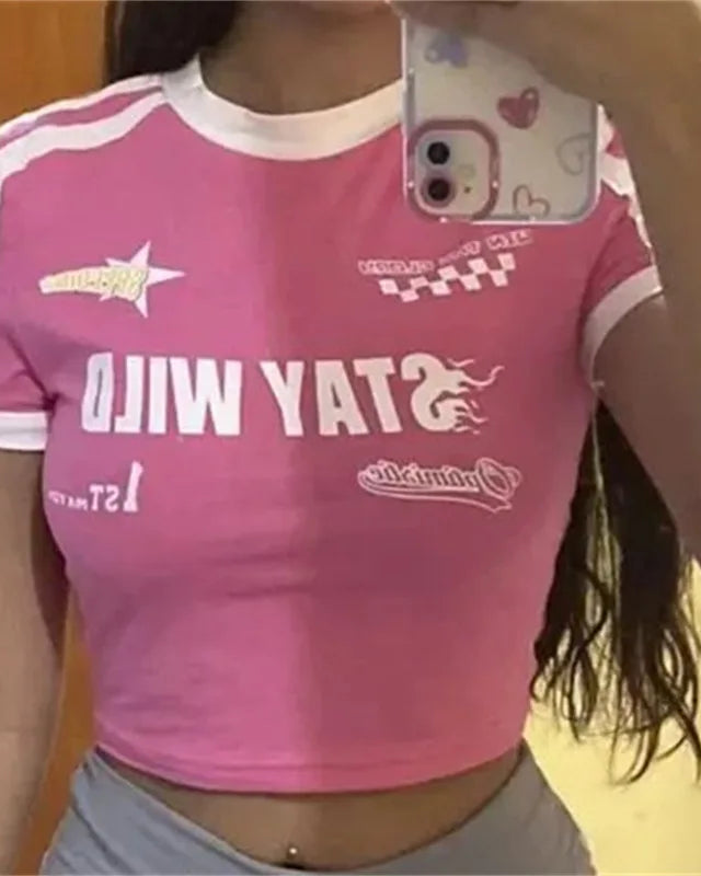 Person wearing a pink crop top with various logos and text.