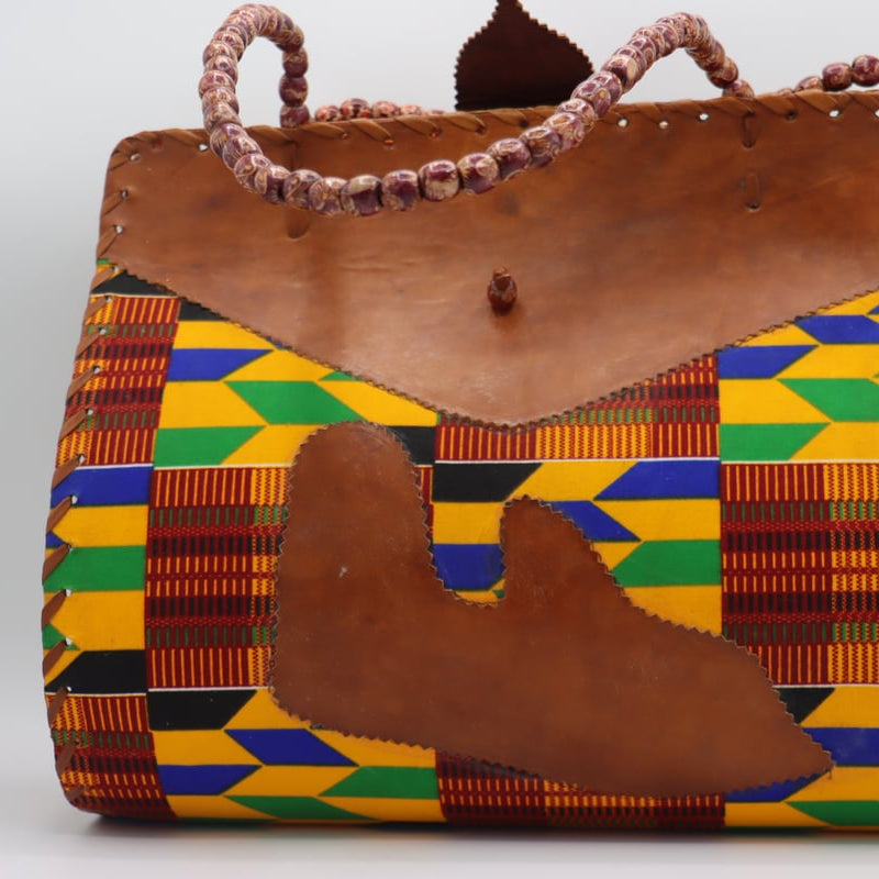 Colorful patterned handbag with a brown leather flap on a white background