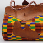 Colorful patterned handbag with a brown leather flap on a white background