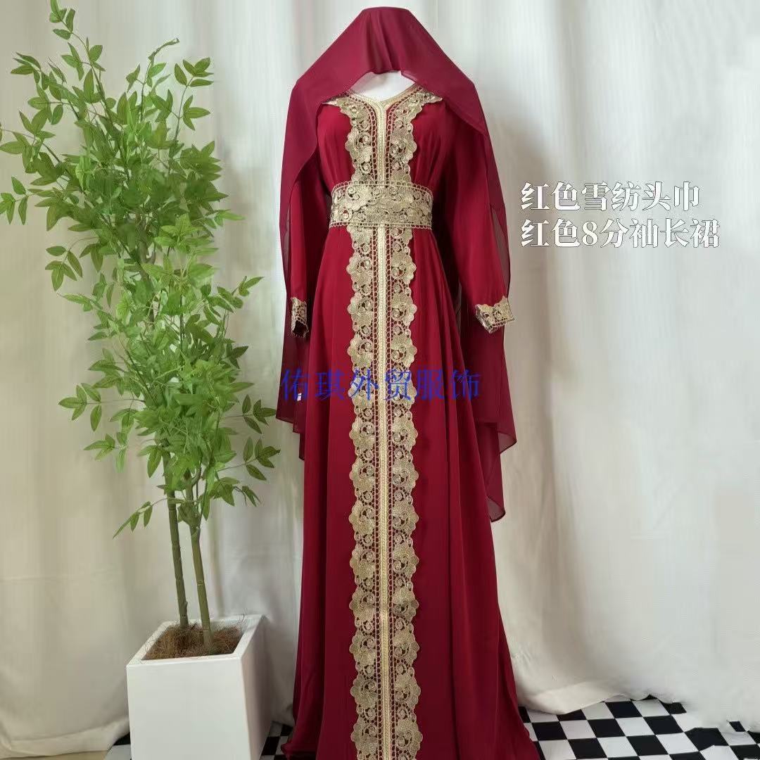 A long red modest dress with gold lace embroidery displayed on a mannequin, with a matching red head covering. The dress features a high neckline, long sleeves, and a full-length skirt with ornate vertical gold embroidery.