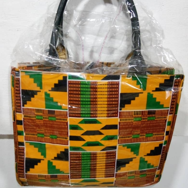 Handbag with a geometric pattern in yellow, green, and brown on a white background